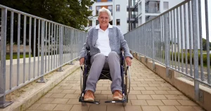 Mulher sorridente em cadeira de rodas ao ar livre, simbolizando amparo financeiro e qualidade de vida proporcionados pela aposentadoria por invalidez.